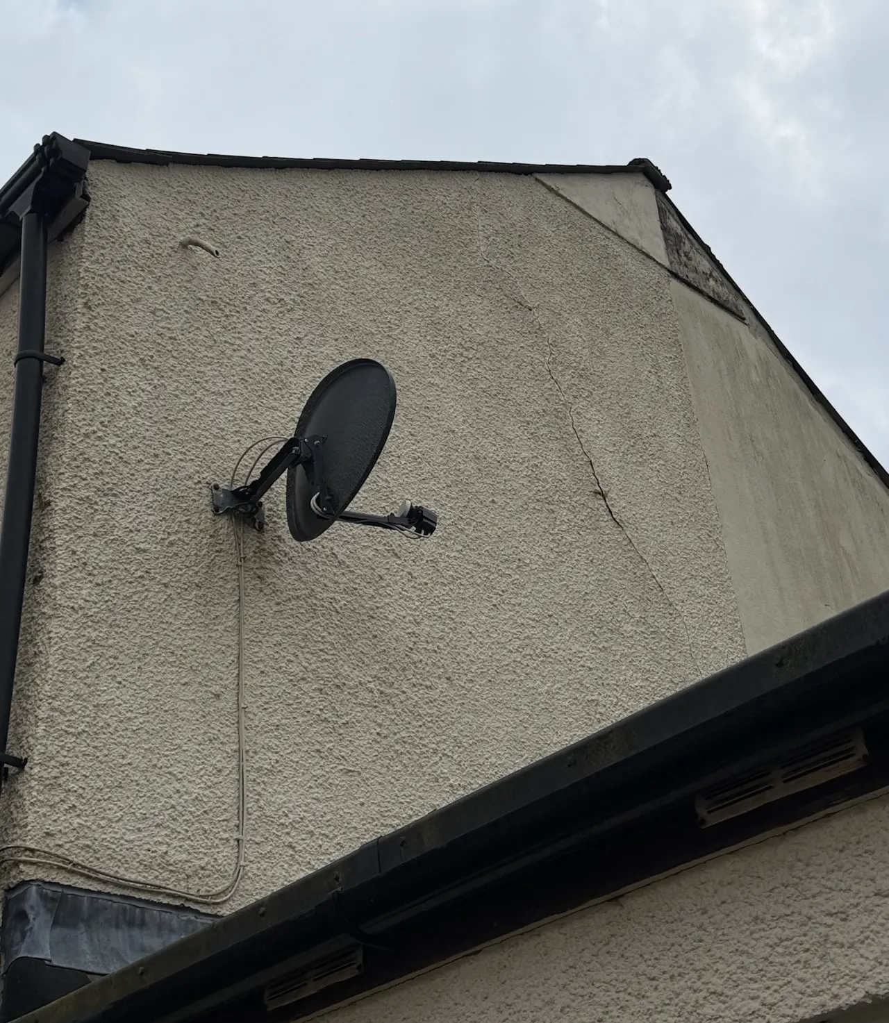 Lateral crack running across the external render of a gable wall, allowing water into the cavity